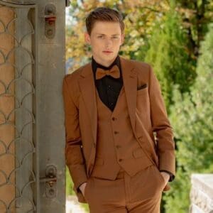 A man in brown suit standing next to a wall.