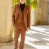 A man in brown suit standing on the sidewalk.