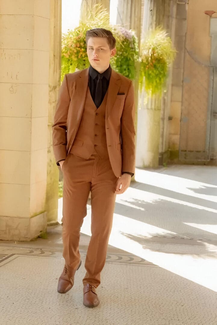 A man in brown suit standing on sidewalk.